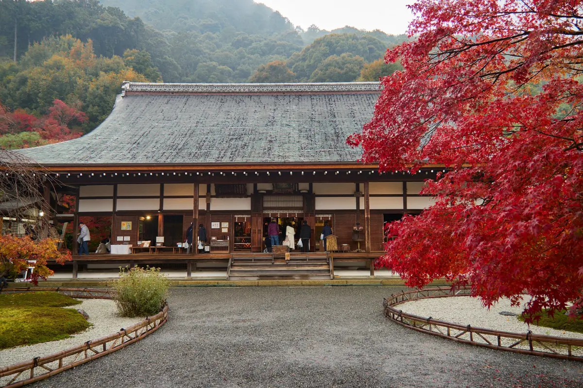 A temple hall framed by autumn leaves