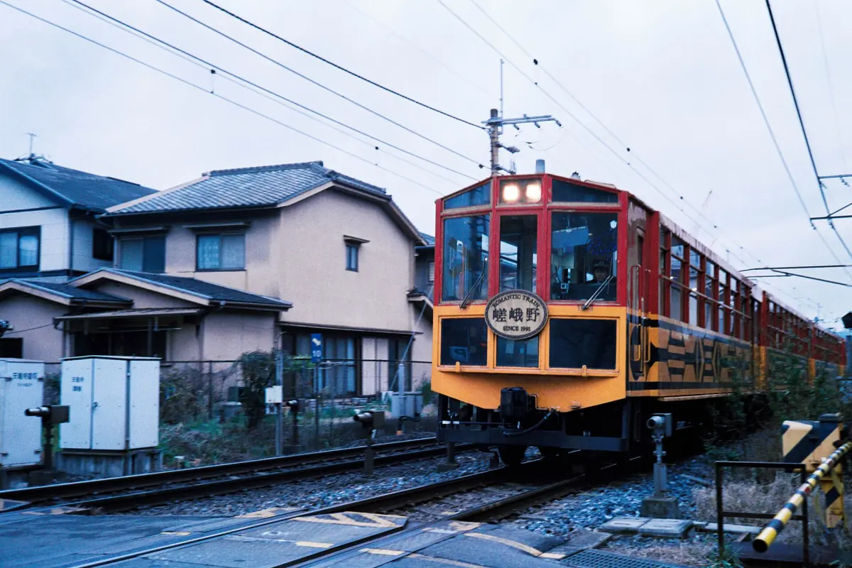 The Sagano Scenic Railway train passing houses